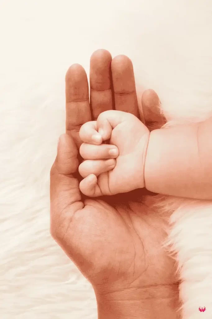 Mano de un adulto sosteniendo la mano de un bebé, representando el vínculo emocional y la protección en un proceso de adopción por excepción.
